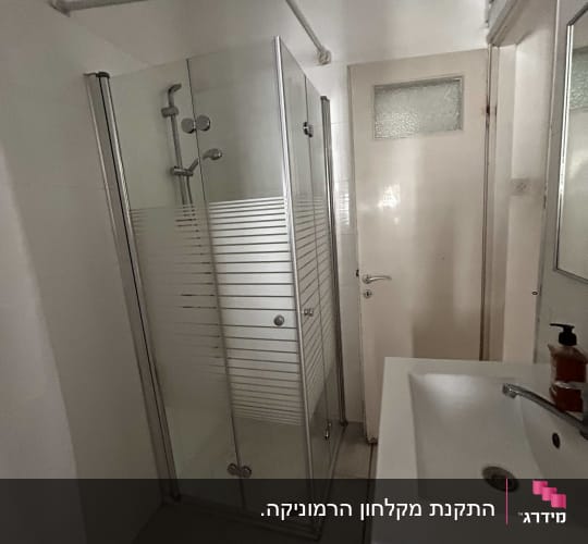 מקלחון זכוכית עם כיור וברז בחדר אמבטיה
